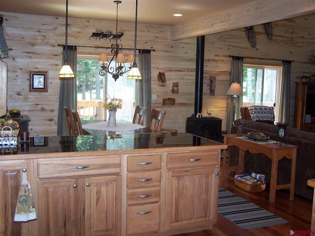 kitchen with decorative light fixtures, wood walls, beam ceiling, a wood stove, and wood finished floors