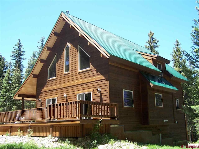 view of side of home with metal roof and a wooden deck