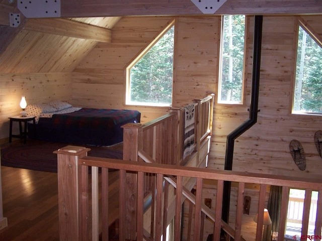 bedroom with wooden walls, wooden ceiling, lofted ceiling with beams, and wood finished floors