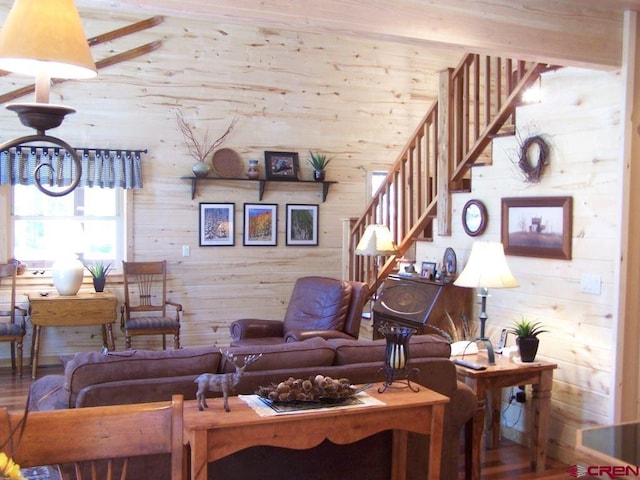 living room with wooden walls, wood finished floors, and stairs