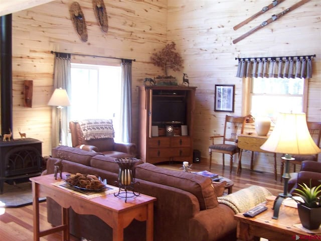 living room with wood finished floors, a wood stove, and wood walls