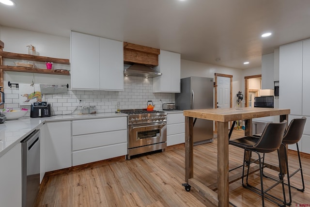 kitchen featuring wall chimney exhaust hood, stainless steel appliances, decorative backsplash, and recessed lighting