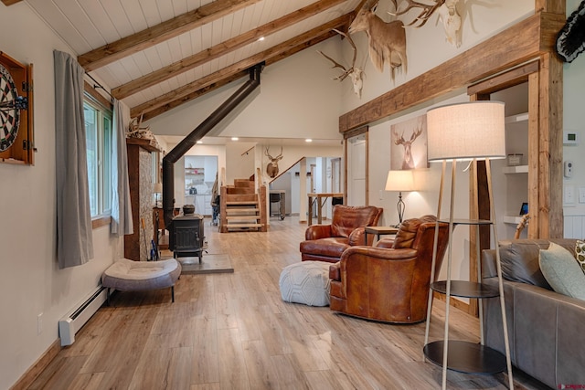 living area featuring beamed ceiling, baseboard heating, stairs, wooden ceiling, and a wood stove