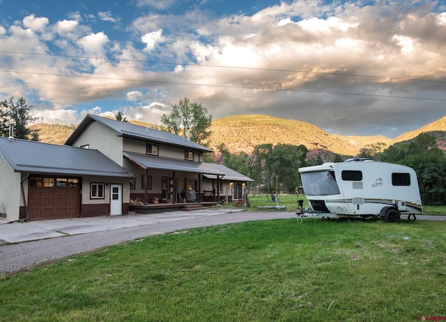 exterior space with an attached garage, a porch, driveway, and a mountain view