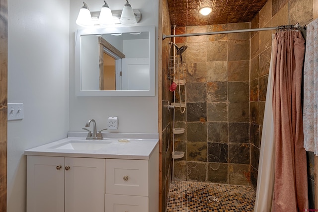 full bath featuring a tile shower and vanity
