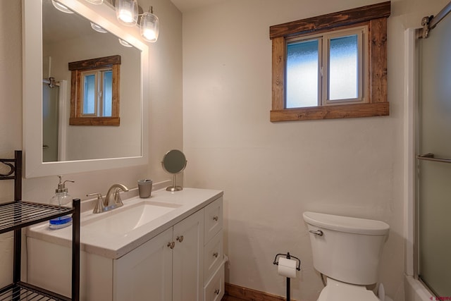 bathroom featuring toilet, vanity, and a shower with door