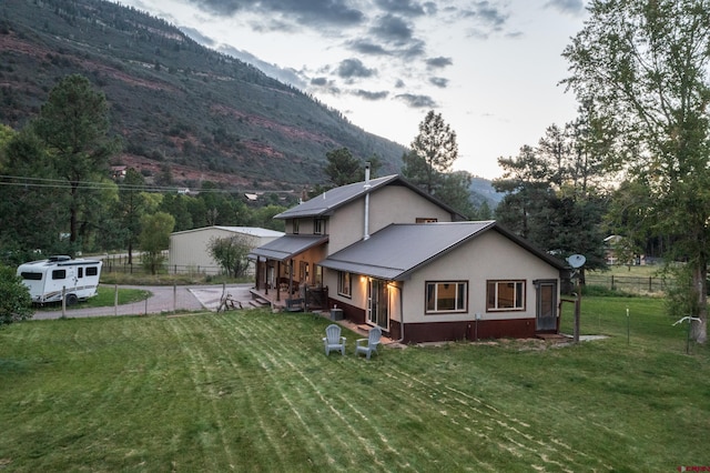 rear view of house with a lawn, fence, and a mountain view