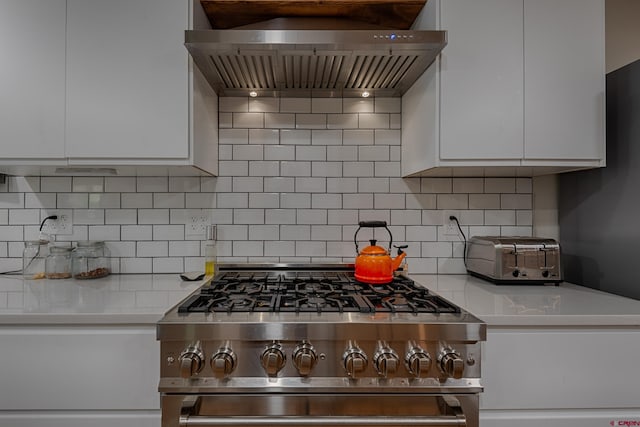 kitchen with high end range, white cabinetry, light countertops, and custom range hood
