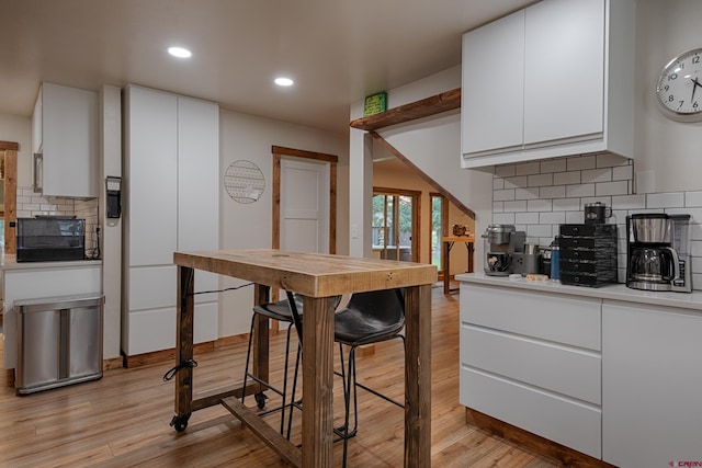 kitchen with light wood-style flooring, recessed lighting, white cabinetry, decorative backsplash, and light countertops