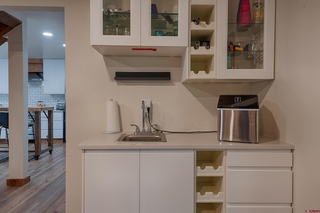bar featuring decorative backsplash, wood finished floors, and a sink