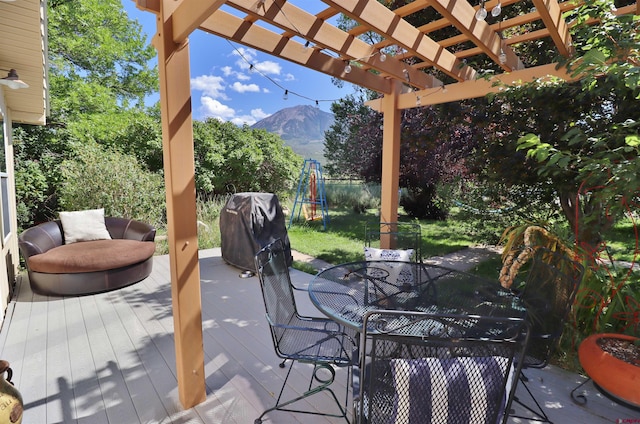 exterior space with grilling area, a deck with mountain view, a trampoline, and a pergola