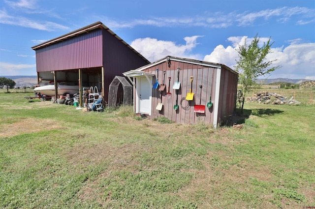 view of outbuilding featuring a lawn, a rural view, and a mountain view