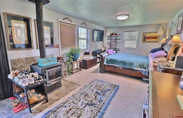 bedroom featuring a wood stove, carpet flooring, and a textured ceiling