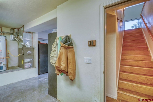 hall featuring water heater, concrete floors, and a textured ceiling