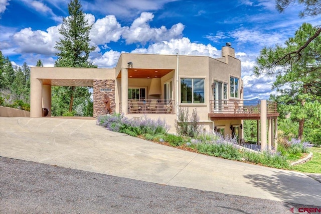994 Cool Pines Dr, Pagosa Springs, CO 81147 - view of front facade featuring a carport, stucco siding, a chimney, and driveway
