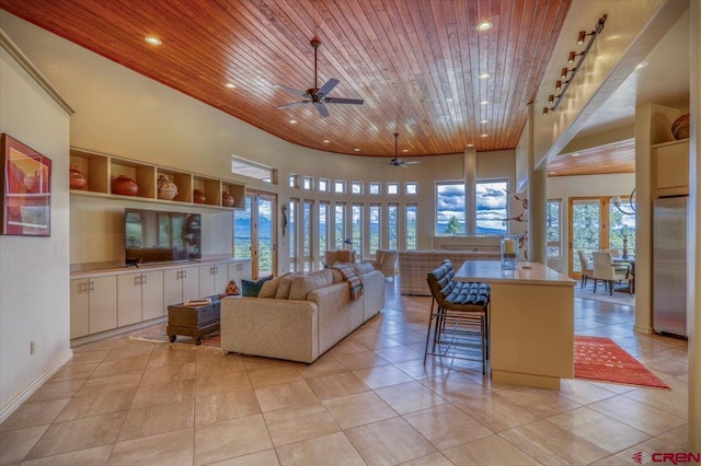 living room with wood ceiling, plenty of natural light, light tile patterned flooring, and ceiling fan