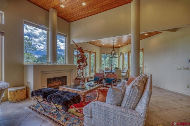 living room featuring wood ceiling, light tile patterned floors, a notable chandelier, and a towering ceiling