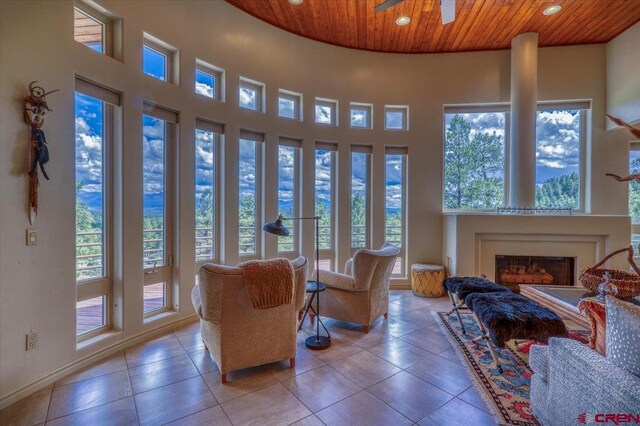 living room featuring a towering ceiling, tile patterned floors, wood ceiling, and ceiling fan