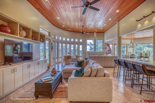 tiled living room featuring wood ceiling, a healthy amount of sunlight, a high ceiling, and ceiling fan with notable chandelier