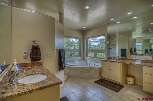 bathroom featuring tiled bath, vanity, and tile patterned floors