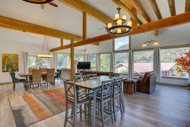 dining space with beamed ceiling, ceiling fan with notable chandelier, high vaulted ceiling, and hardwood / wood-style flooring