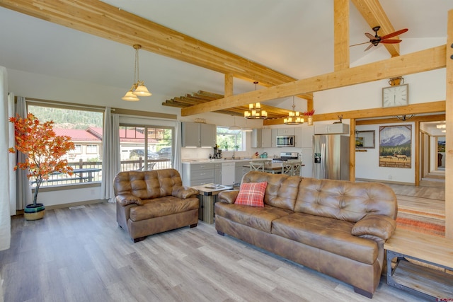 living room with ceiling fan with notable chandelier, beamed ceiling, sink, and light hardwood / wood-style floors