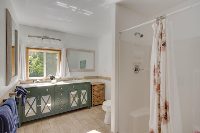 bathroom featuring a shower with shower curtain, wood-type flooring, toilet, and vanity