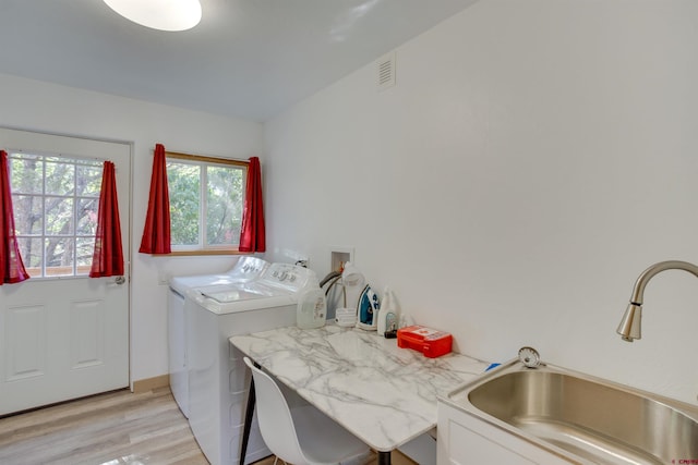 washroom featuring washing machine and dryer, sink, and light hardwood / wood-style floors