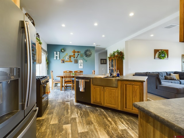 kitchen with a kitchen island with sink, dark wood-type flooring, stainless steel appliances, and sink