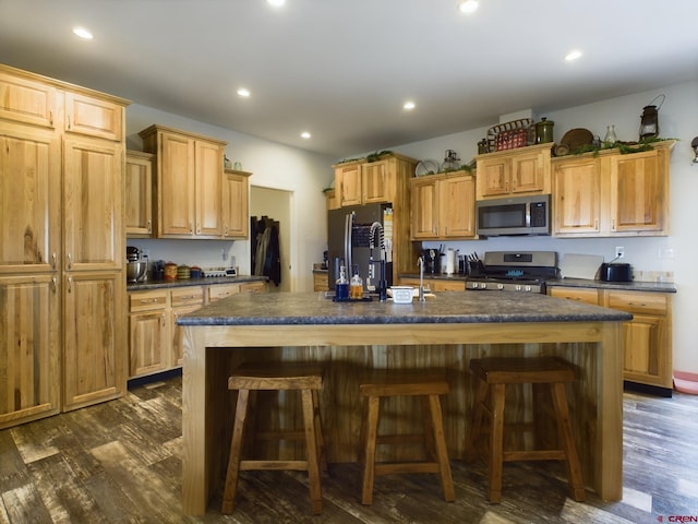 kitchen featuring an island with sink, dark hardwood / wood-style floors, and appliances with stainless steel finishes