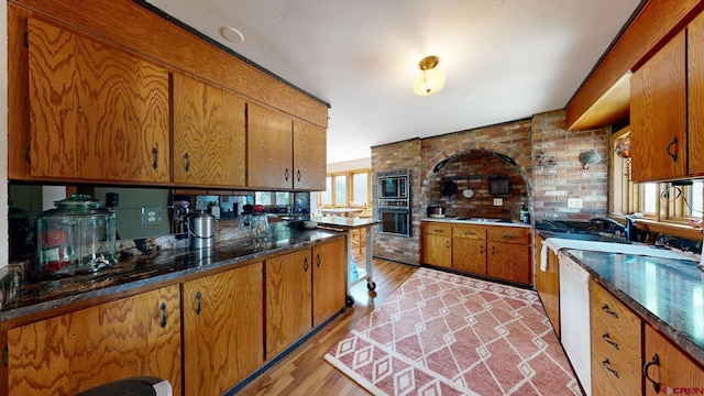 kitchen featuring a wealth of natural light, light hardwood / wood-style flooring, and black oven