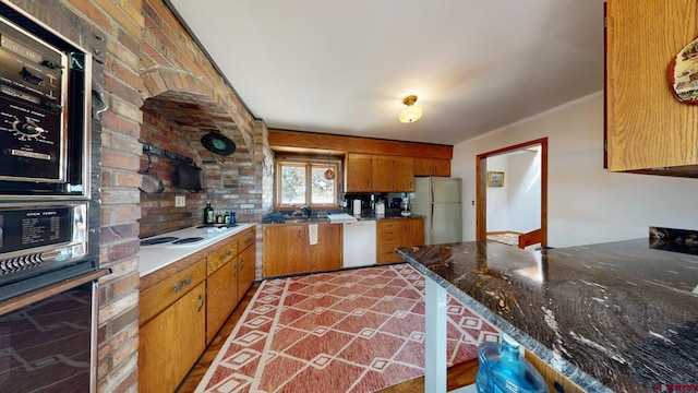 kitchen featuring white appliances, ornamental molding, brick wall, and sink