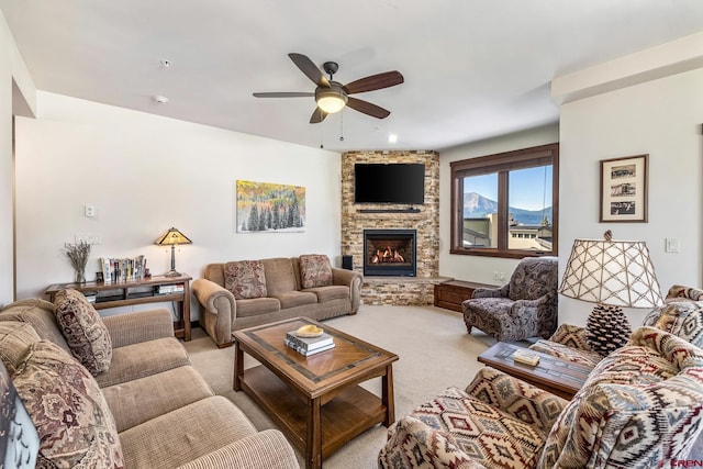 carpeted living room featuring ceiling fan and a stone fireplace