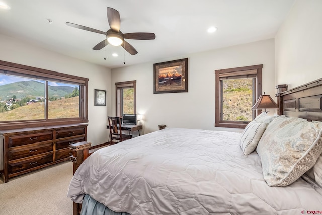 bedroom featuring ceiling fan, light carpet, and a mountain view