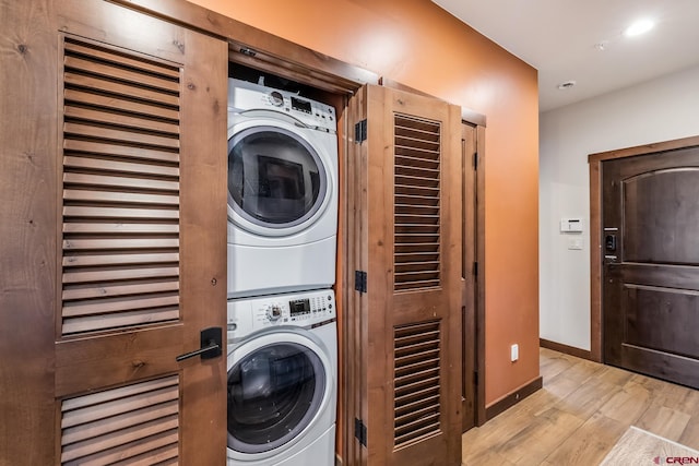 laundry area with light hardwood / wood-style floors and stacked washing maching and dryer