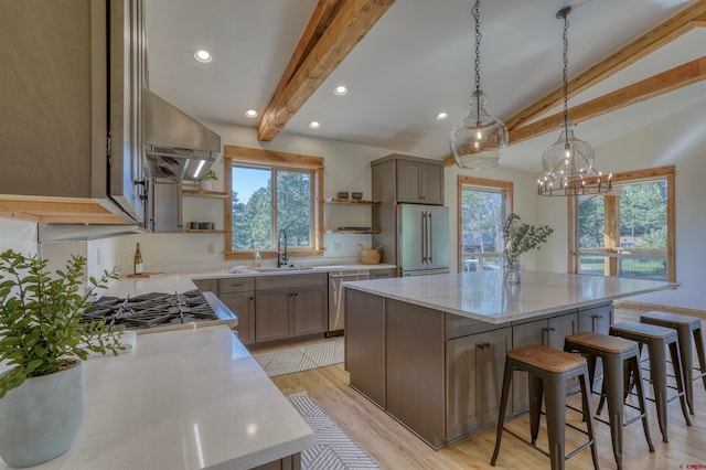 kitchen with stainless steel appliances, exhaust hood, a kitchen island, lofted ceiling with beams, and a breakfast bar area