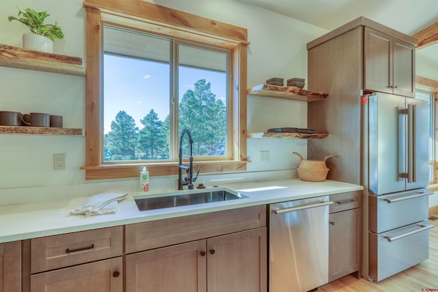 kitchen with light wood-type flooring, appliances with stainless steel finishes, and sink