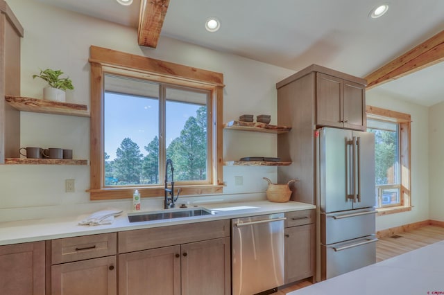 kitchen with stainless steel dishwasher, a healthy amount of sunlight, sink, and high end fridge