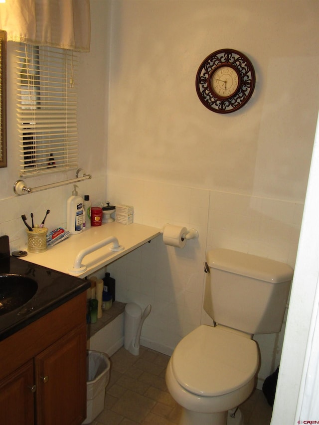 730 Washington St, Monte Vista, CO 81144 - bathroom featuring a wainscoted wall, toilet, vanity, and tile walls