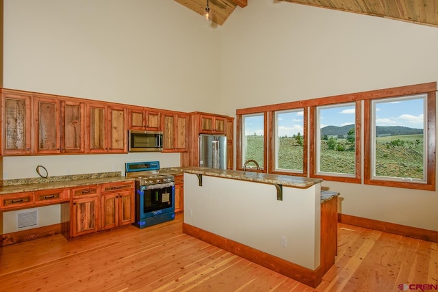 kitchen featuring beamed ceiling, high vaulted ceiling, light hardwood / wood-style flooring, stainless steel appliances, and a breakfast bar