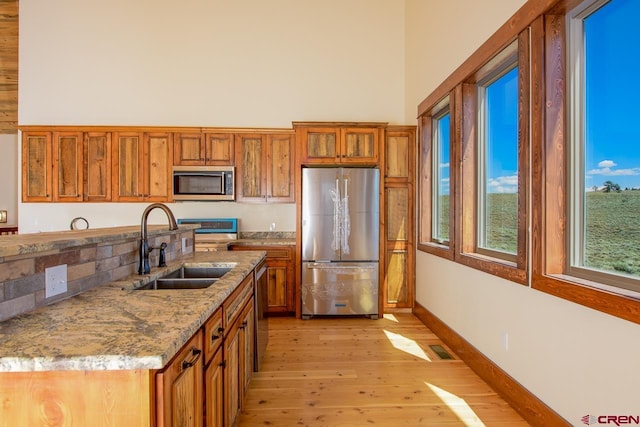 kitchen featuring light hardwood / wood-style flooring, appliances with stainless steel finishes, light stone counters, and sink