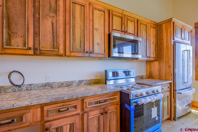 kitchen featuring stainless steel appliances, light stone counters, and light hardwood / wood-style floors