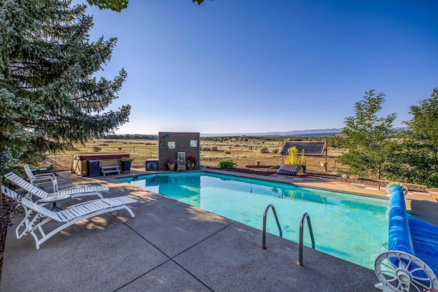 view of swimming pool featuring a rural view and a patio