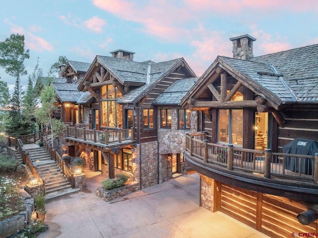 back house at dusk with a patio and a balcony