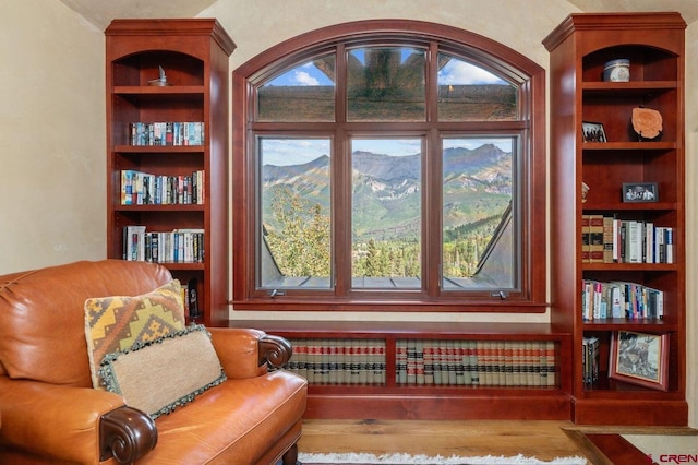 sitting room with built in shelves and hardwood / wood-style flooring