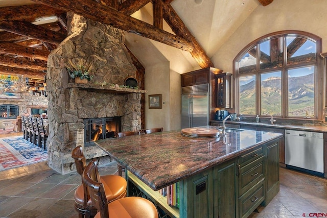 kitchen featuring a breakfast bar area, appliances with stainless steel finishes, a kitchen island, and beam ceiling