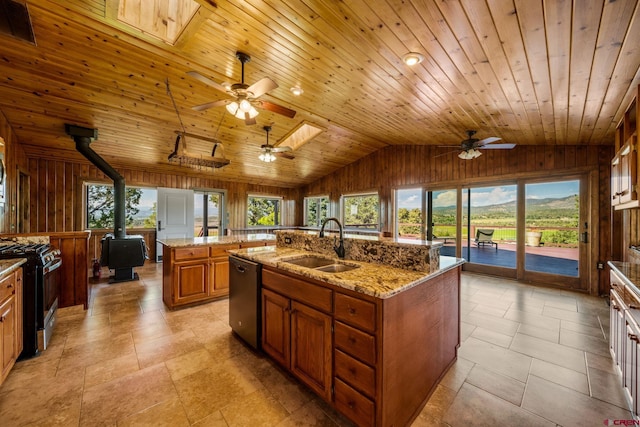 kitchen with a kitchen island with sink, wood ceiling, a wood stove, and ceiling fan