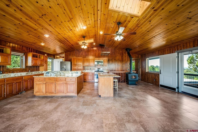 kitchen with wood ceiling, a wood stove, ceiling fan, a kitchen island, and a breakfast bar