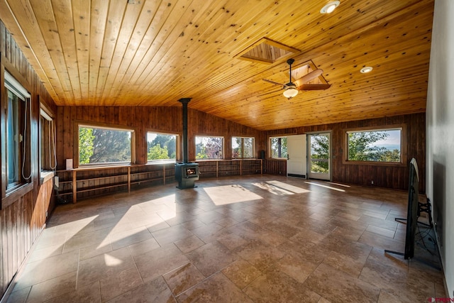 interior space featuring wooden ceiling, lofted ceiling with skylight, ceiling fan, and a wood stove