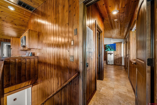 hallway with wood ceiling, vaulted ceiling, and wooden walls